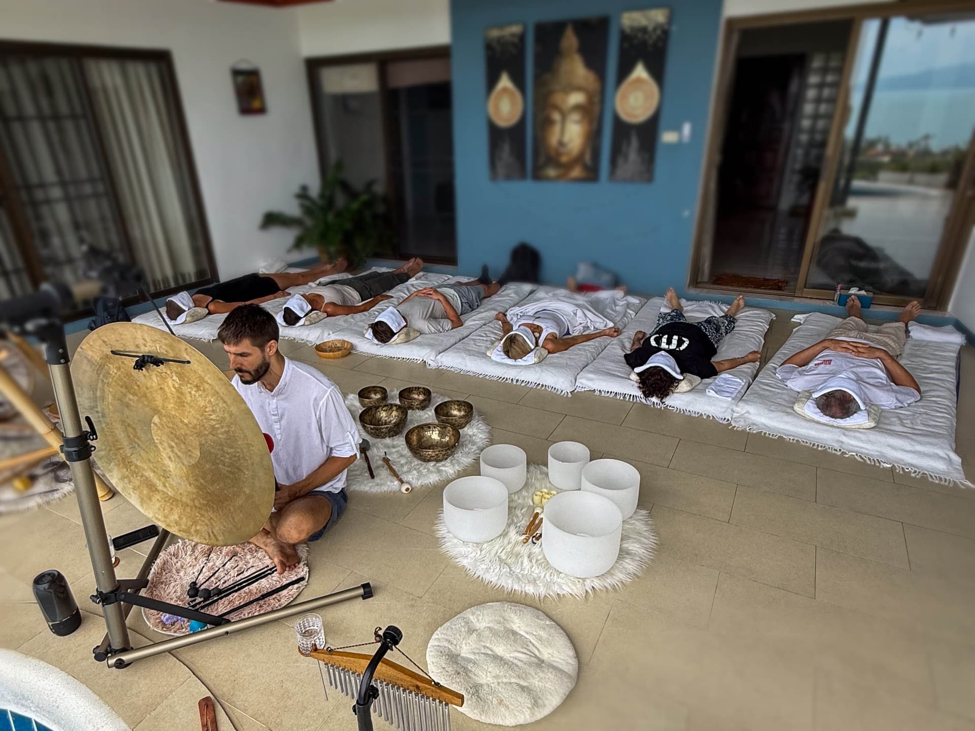 Group sound journey with participants resting on mats in a serene studio.